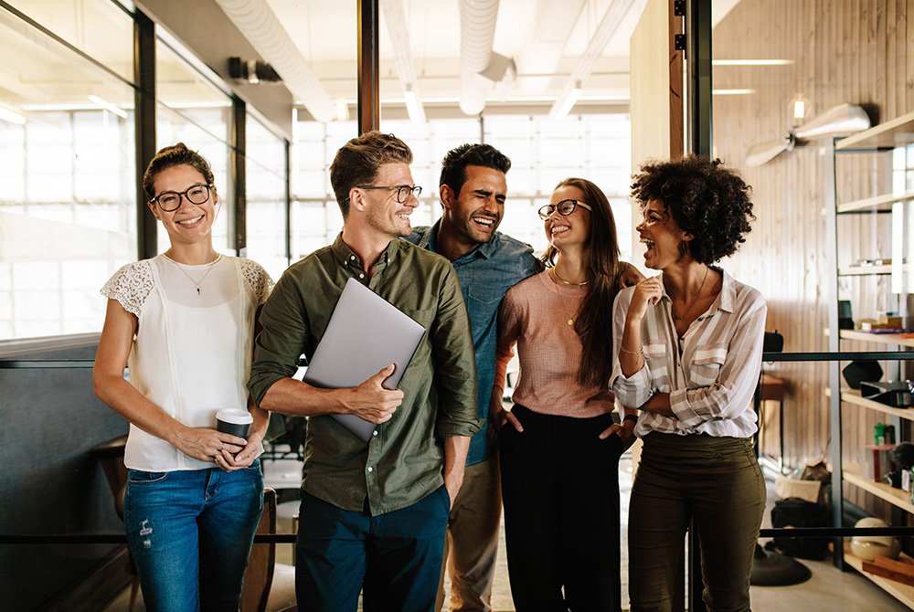 group of employees standing and smiling in the office