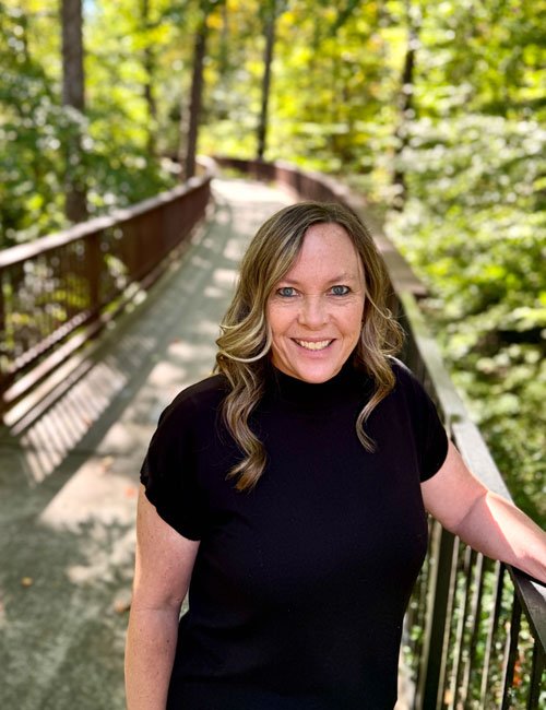 Lori Marchant smiling infront of flowers